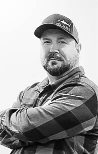 Josh Edmondson, Co-Owner of The Generator Guys, wearing a plaid shirt and cap, posing confidently to represent the company's commitment to reliable generator services in Sussex County, DE.